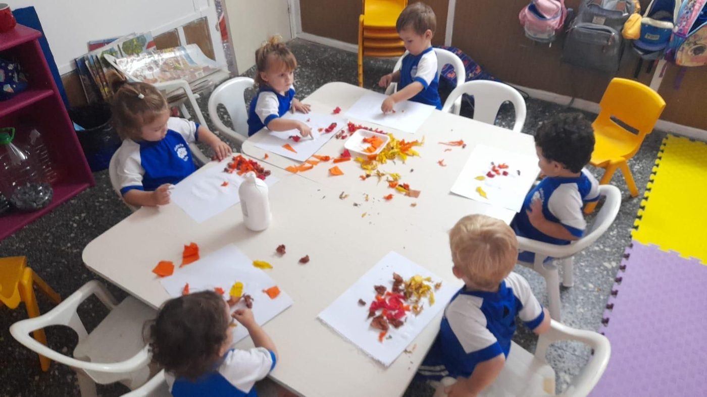 Niños trabajando con papeles de colores en el taller de plástica
