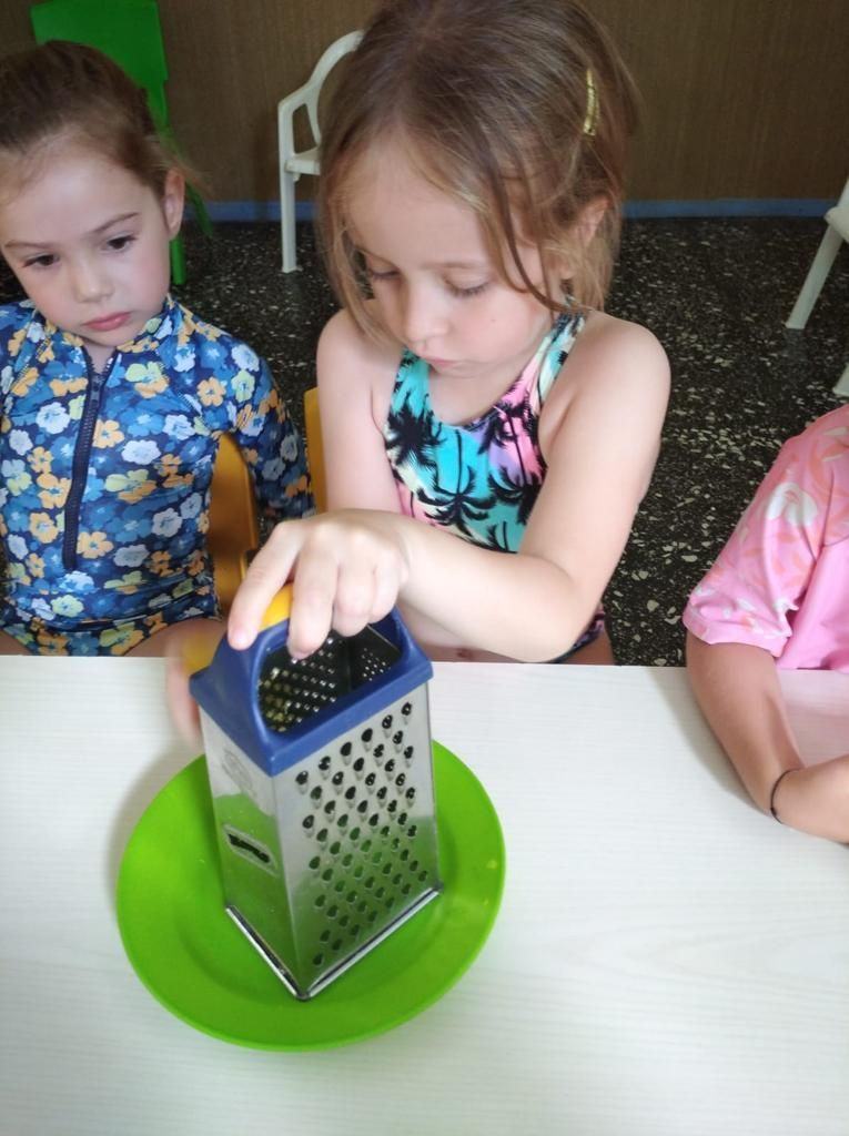 Niña rallando queso en el taller de cocina