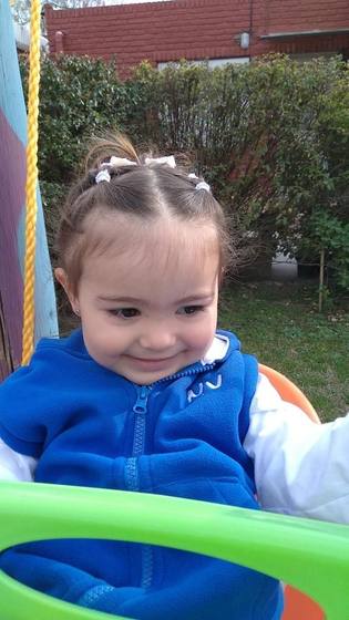 Niña sonriendo en la hamaca del patio